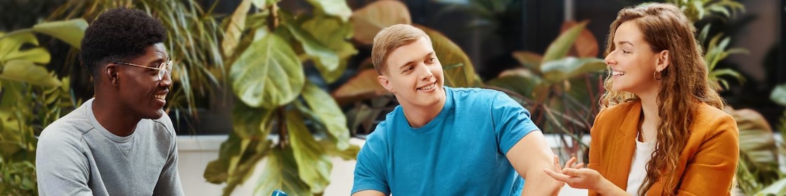 Two men and a woman sitting on benches in a modern indoor space