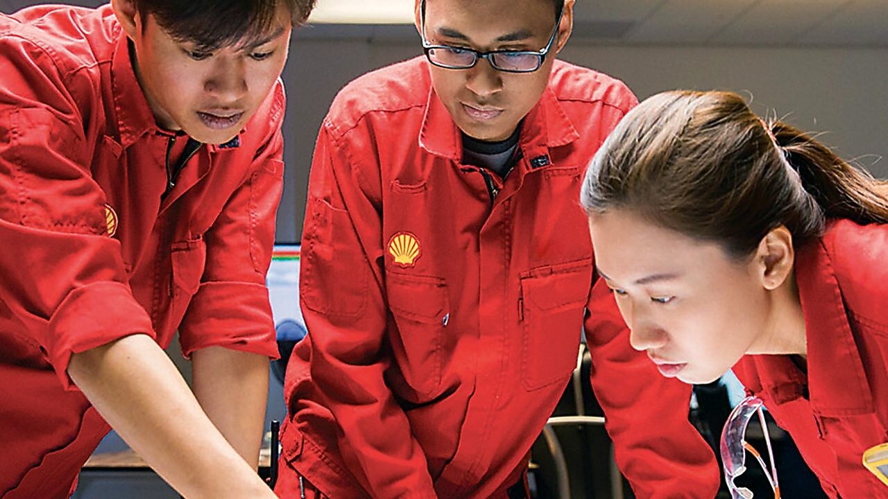 Diverse employees standing discussing while one is writing on the glass board.