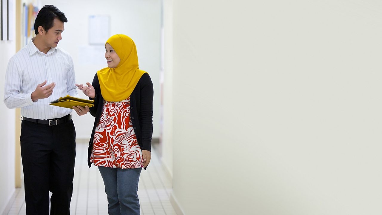 Employees walking and talking in corridor with iPad
