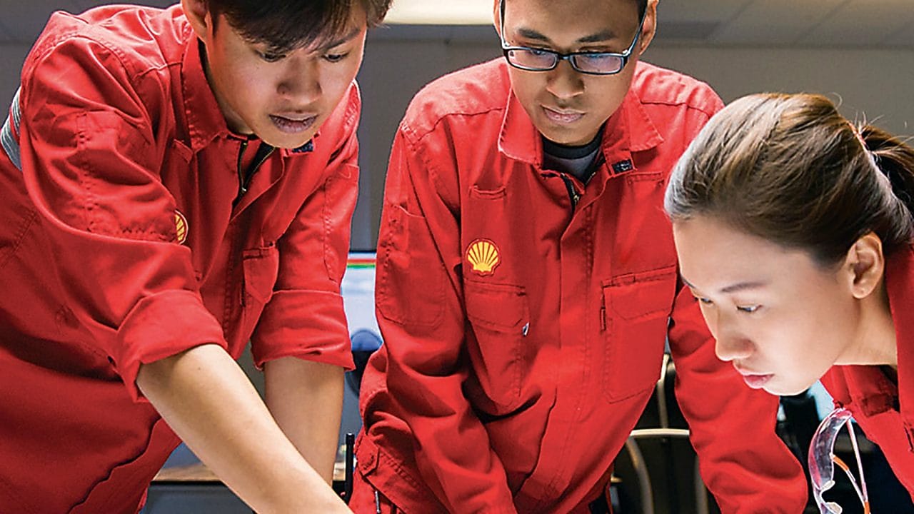 Diverse employees standing discussing while one is writing on the glass board.