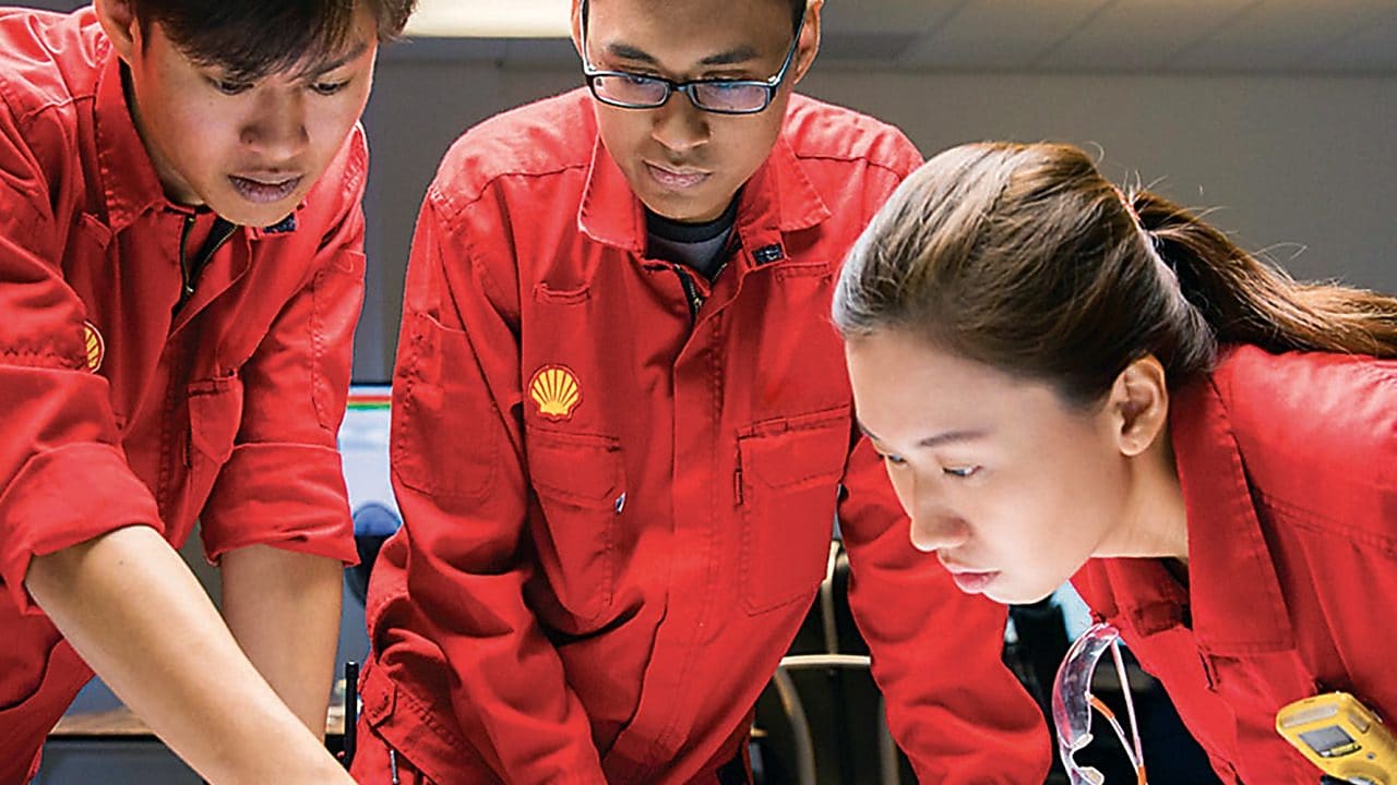Diverse employees standing discussing while one is writing on the glass board