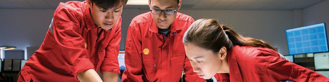 Diverse employees standing discussing while one is writing on the glass board