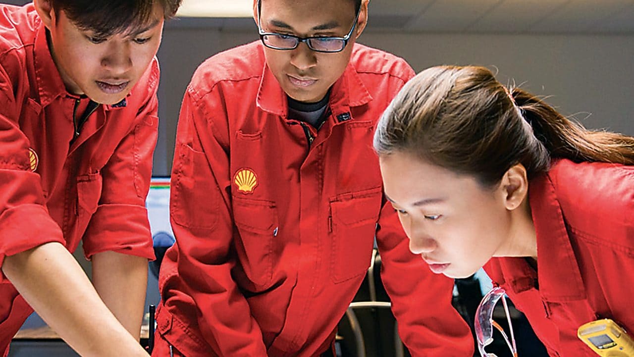 Diverse employees standing discussing while one is writing on the glass board
