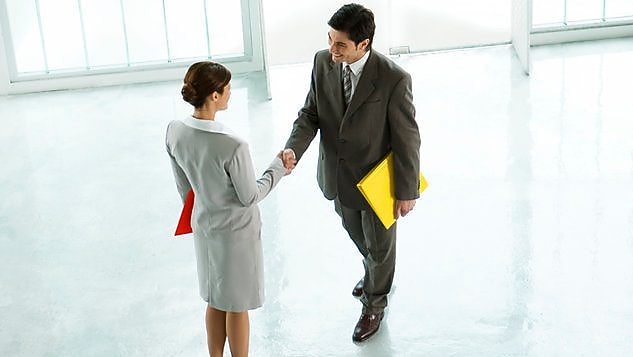 Businessman and businesswoman shaking hands in lobby