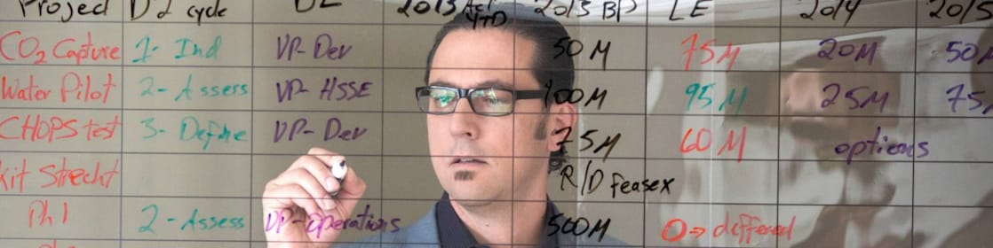 employee writing on transparent board.