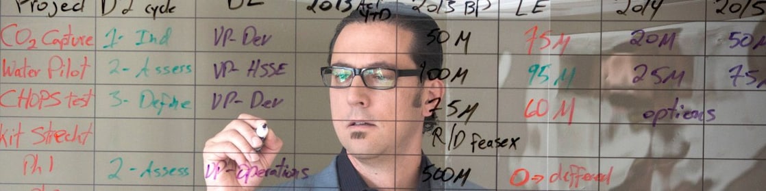 employee writing on transparent board.