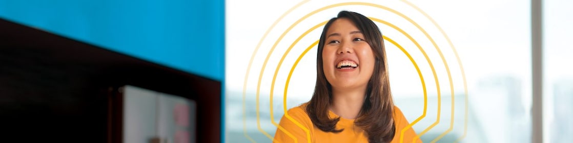 A female Shell employee in the office happily gazing afar.