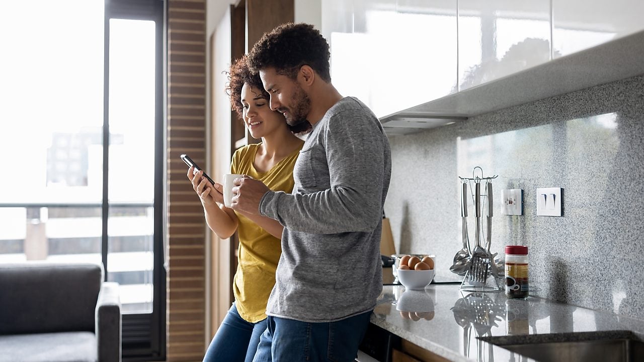 Man and woman at home using mobile phone