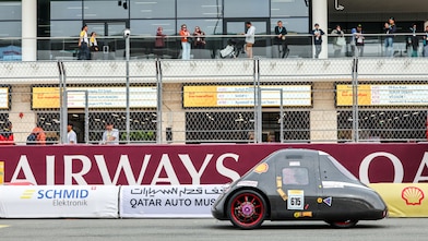 Temasek Polytechnic’s TP EcoFlash vehicle competes on the track during the Shell Eco-marathon, with spectators watching from the grandstand.