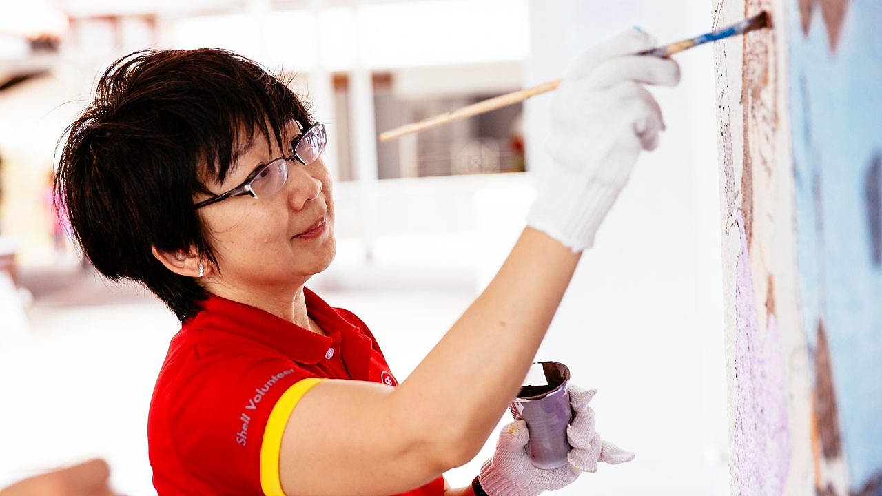 Shell volunteer Christine Low hard at work and play in painting one of the murals.
