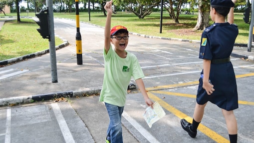 A boy raising his hands while crossing the road at the mini Shell Traffic Games