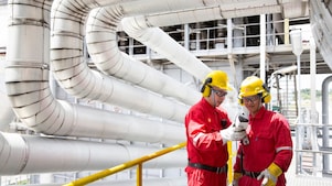Two engineers are checking on the readings on a device at the manufacturing plant.