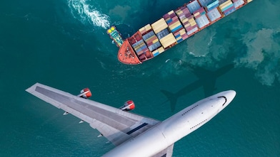 Aerial view of a plane flying past a cargo ship that was leaving the harbour, with a truck boat spinning a large ship.