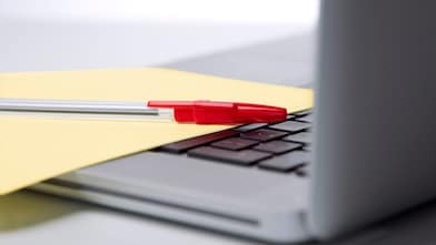 Photo of red pan on yellow piece of paper, placed on the keyboard of a laptop