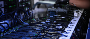 A gloved hand next to an assortment of wires connecting to a computer system.