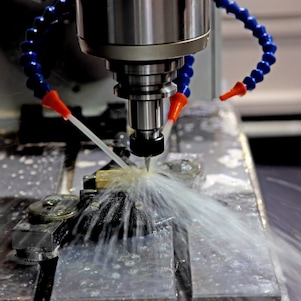 An oil drill being worked, and water being pumped onto it to help cool it down