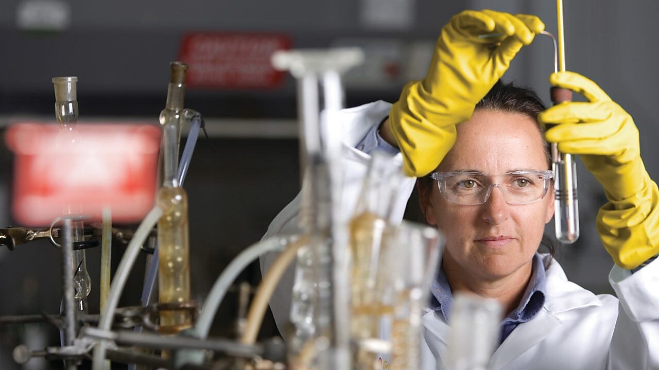 lady in safety goggles conducting a lab experiment
