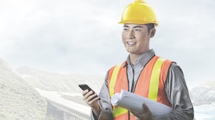 man wearing a yellow safety helmet holding a phone