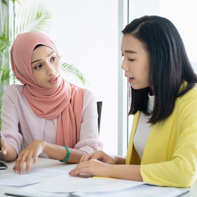 Female inspector discussing with engineer in car factory. Multi-ethnic male and female professionals are standing at car production line. They are in automotive industry.