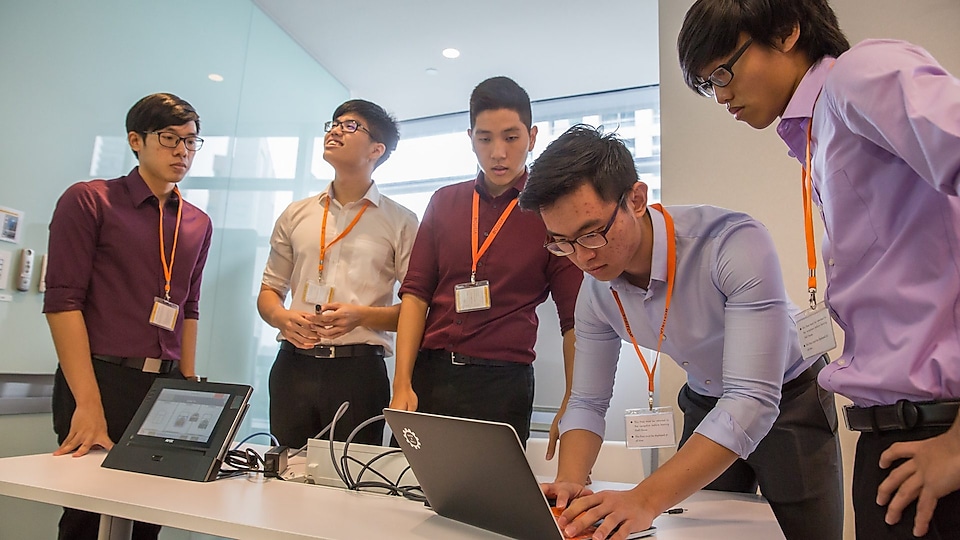 Group of singapore students discussing on laptop