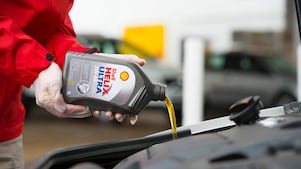 Man filling Shell Helix Ultra oil in car