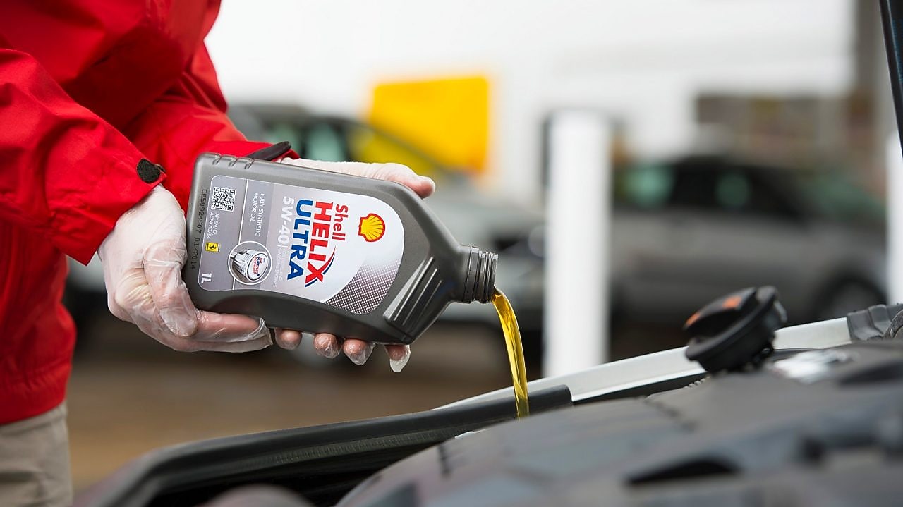 Man filling Shell Helix Ultra oil in car