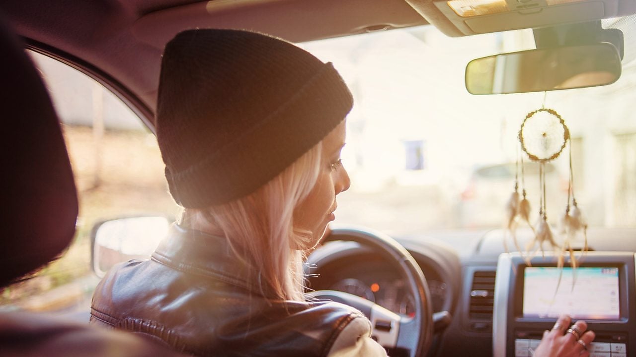 A young woman checks the instructions displayed on her car's built-in navigation screen