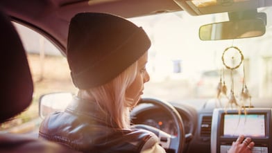 A young woman checks the instructions displayed on her car's built-in navigation screen