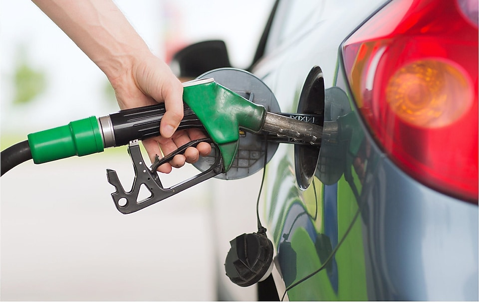 Hand holding a pump nozzle, refueling the car