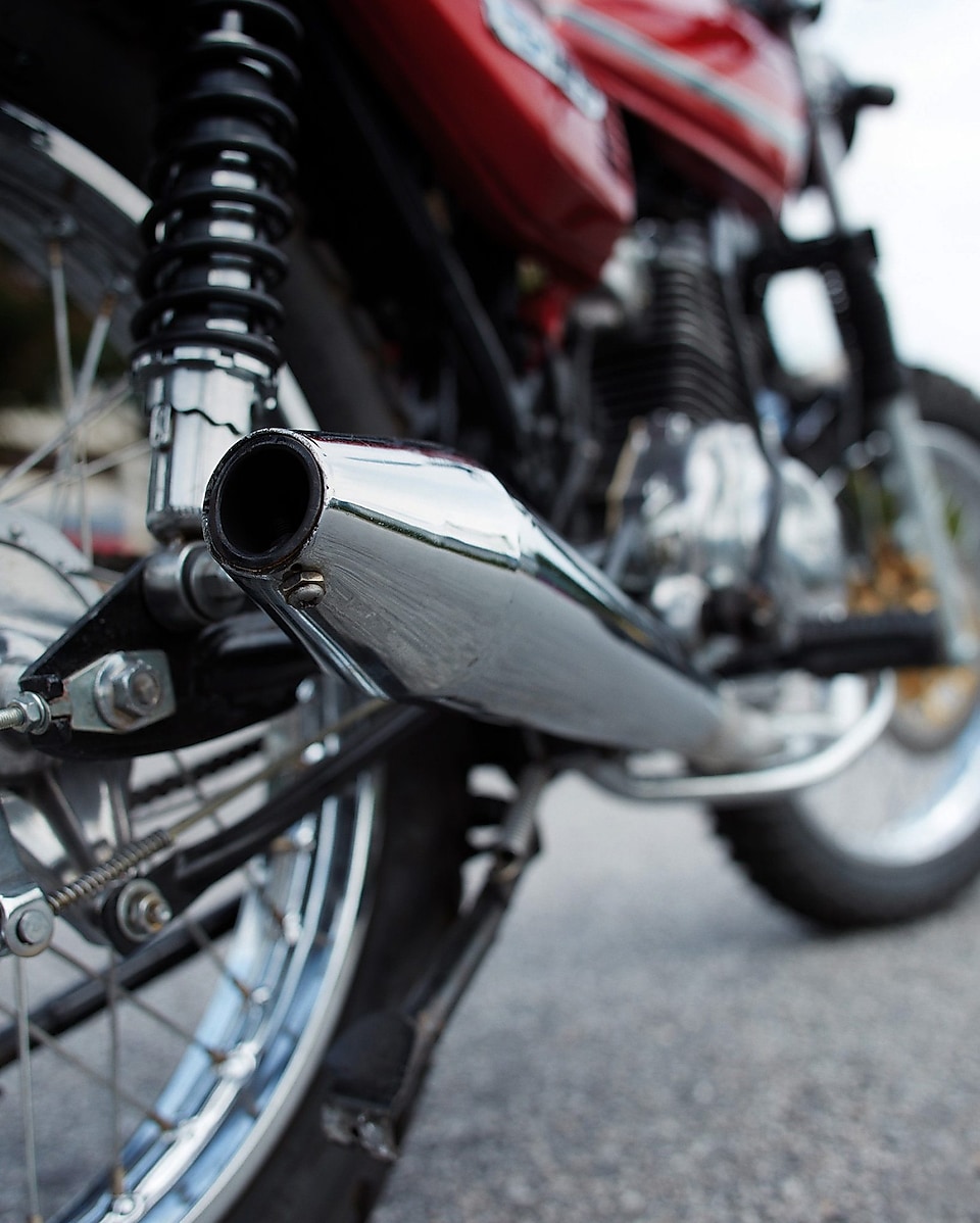 motorcycle parked on road with camera focused on the exhaust and wheels