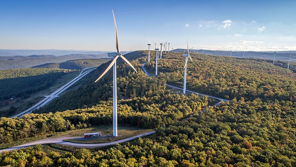Wind turbine, wind farm in green field with dirt road.