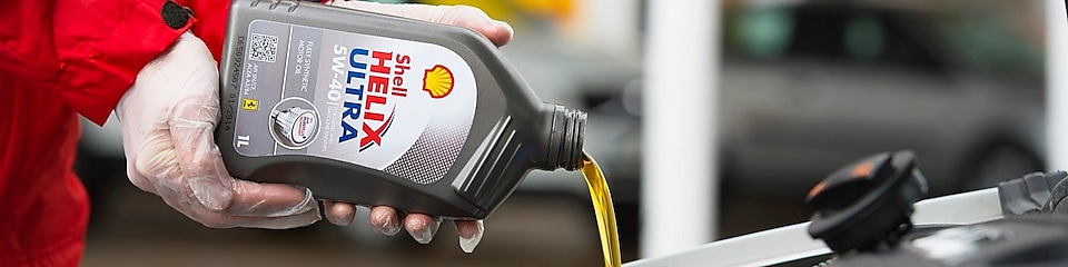 Man filling Shell Helix Ultra oil in car