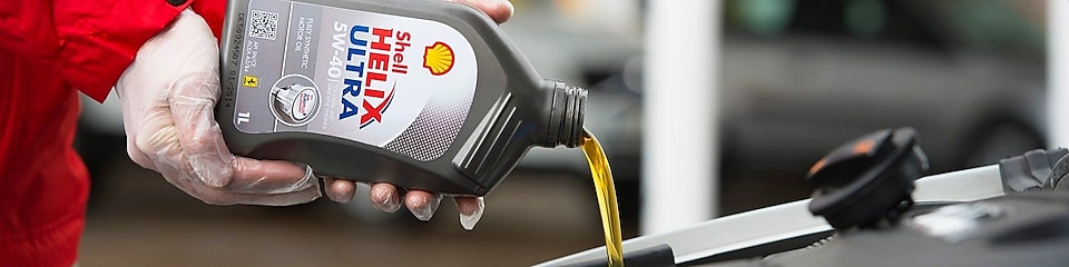 Man filling shell helix ultra oil in car
