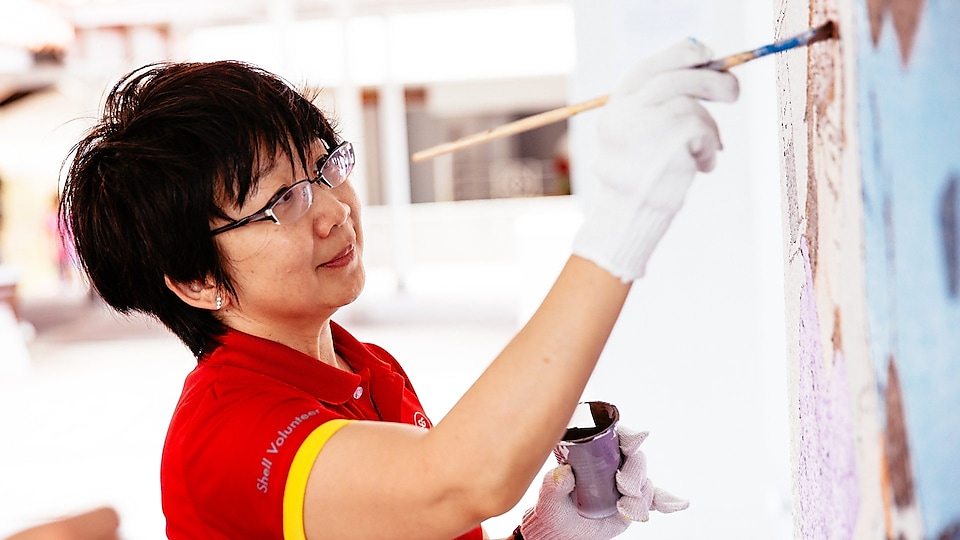 Shell volunteer Christine Low hard at work – and play – in painting one of the murals.