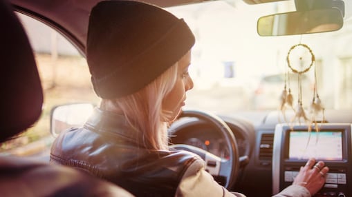A young woman checks the instructions displayed on her car's built-in navigation screen
