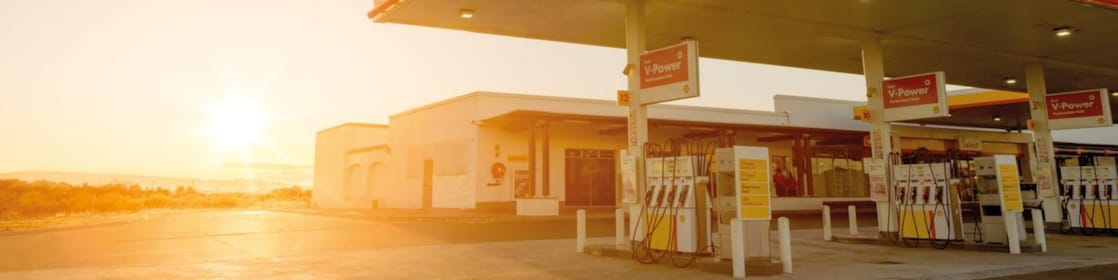 Sun rising behind a Shell station forecourt