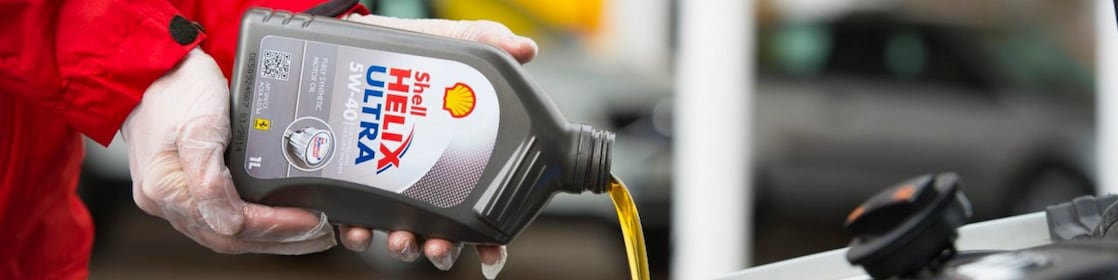 Man filling shell helix ultra oil in car
