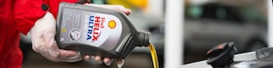 Man filling shell helix ultra oil in car