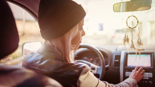 A young woman checks the instructions displayed on her car's built-in navigation screen