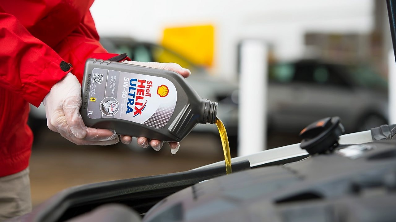 Man filling shell helix ultra oil in car