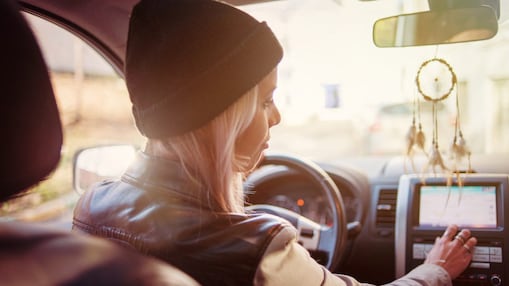 A young woman checks the instructions displayed on her car's built-in navigation screen