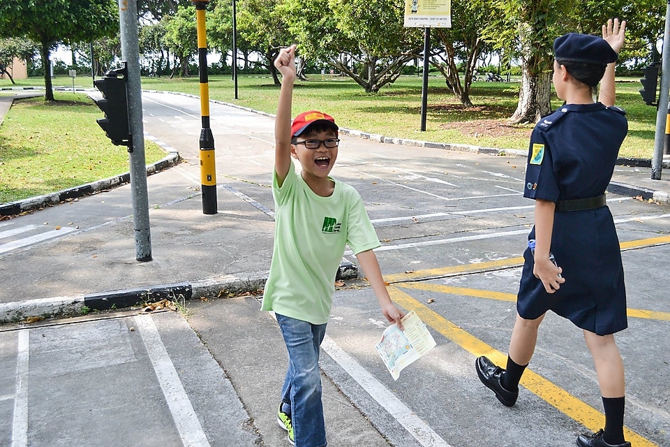 A boy raising his hands while crossing the road at the mini Shell Traffic Games